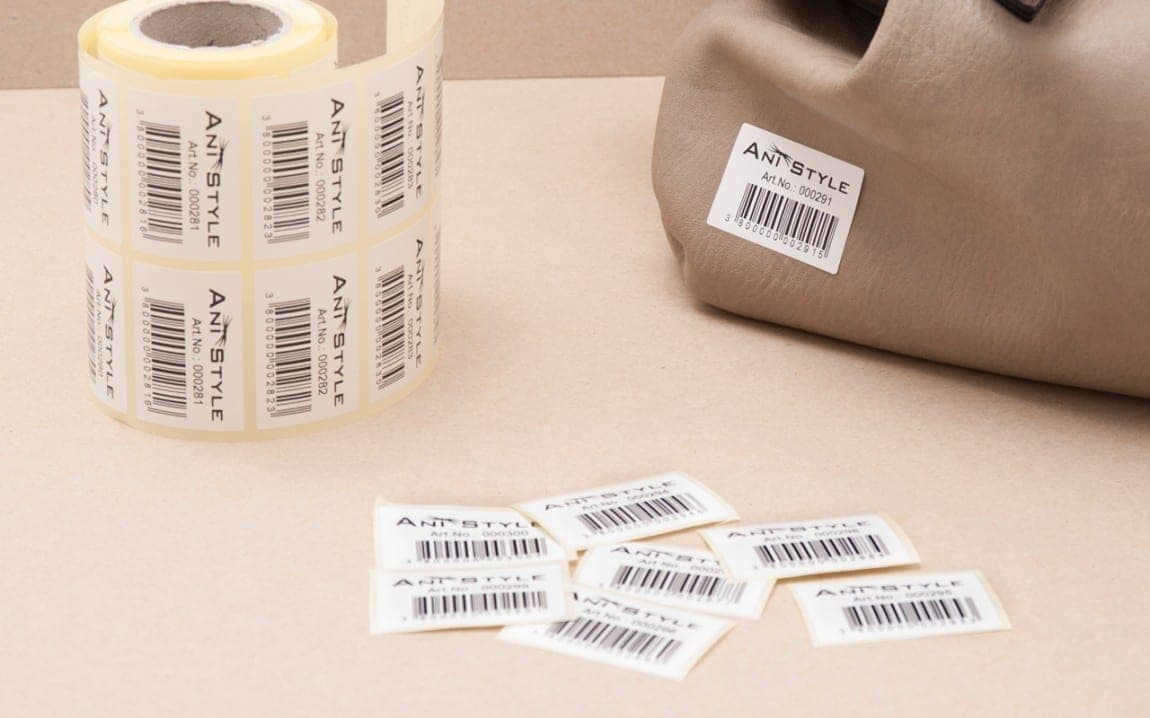 Rolls of white barcode labels next to printed barcode tags